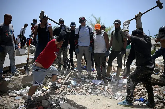 Voluntarios golpean restos de concreto con mazos de hierro buscando sobrevivientes bajo los escombros en La Guaira, Venezuela, 26 de junio 2026